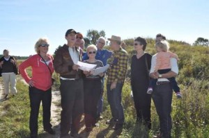 Bill in Herman's flight jacket and the group review the photos and try to identify the landing site.